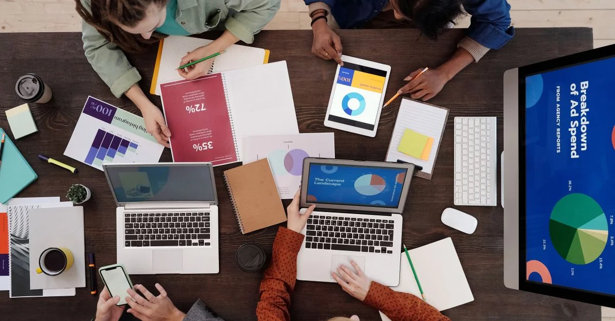 Une équipe diversifiée collaborant sur des stratégies de marketing numérique à un bureau, utilisant des ordinateurs portables et des tablettes.