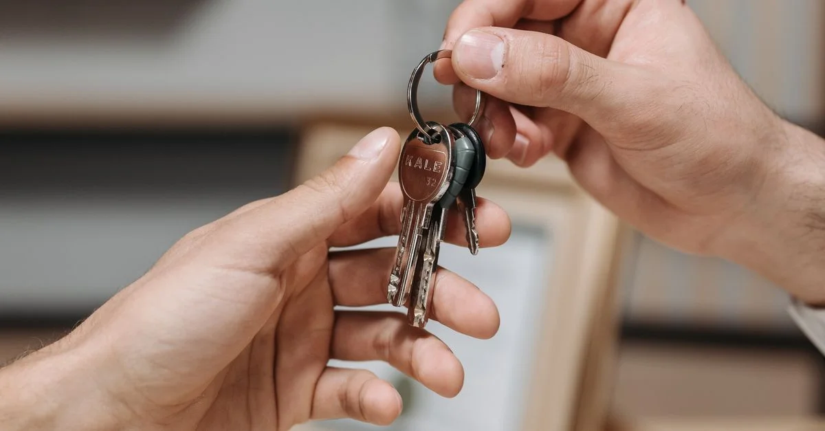 Une image en gros plan de deux mains échangeant un trousseau de clés à l'intérieur.