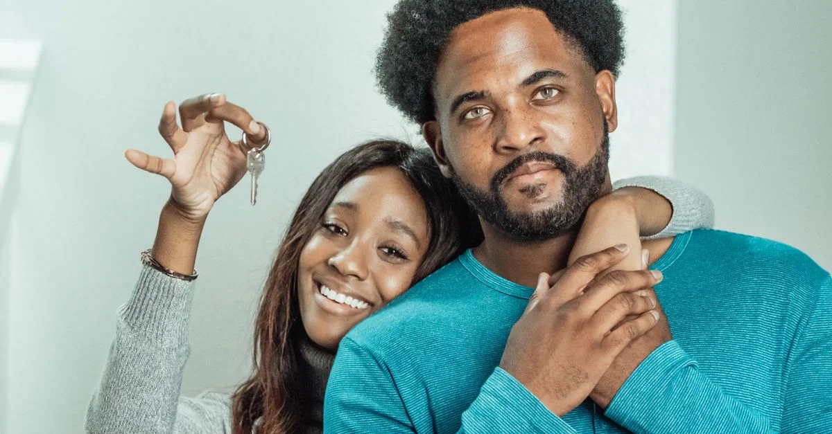 Un couple souriant célèbre la réception des clés de leur nouvelle maison à l'intérieur.