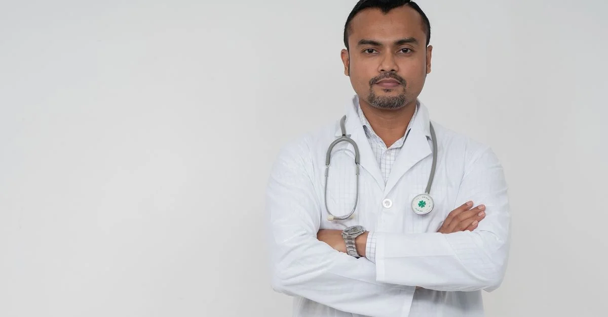 Médecin masculin sud-asiatique confiant en manteau blanc avec un stéthoscope, photo portrait.